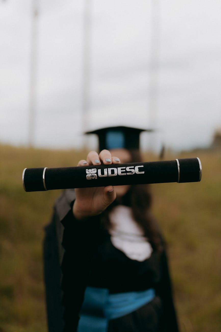 graduate holding diploma in cap and gown