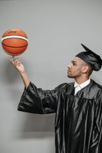 photo of man in black academic gown holding basketball
