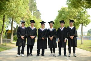 young graduates celebrating outdoors in cap and gown